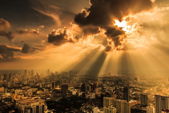 Rays of light shining through dark clouds with city below